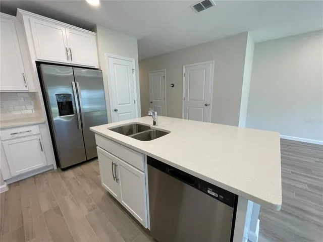 a kitchen with a sink a refrigerator and cabinets
