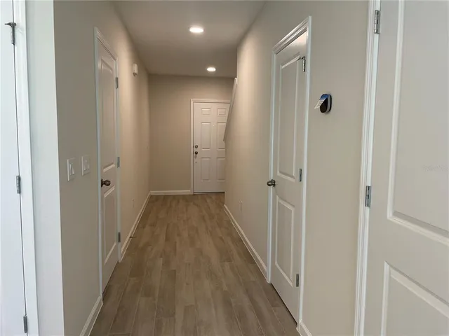 a view of a hallway with wooden floor and a bathroom