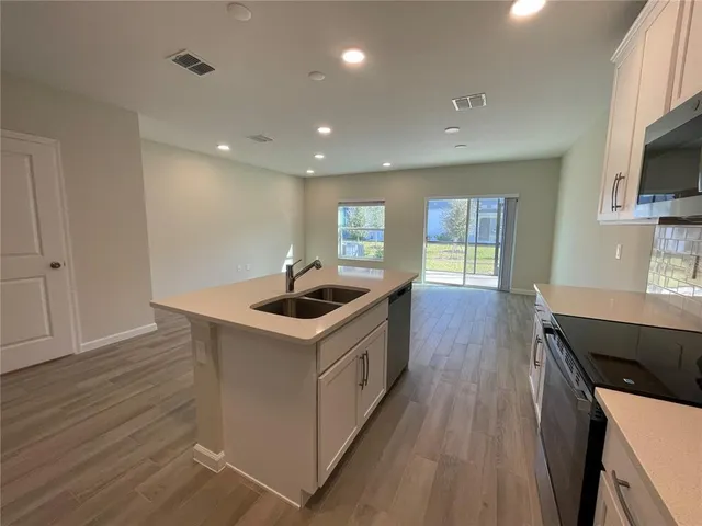 a kitchen that has a lot of cabinets a sink and wooden floor