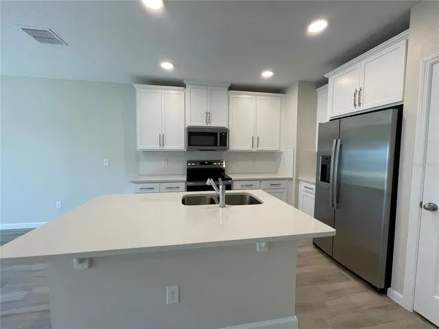 a kitchen with stainless steel appliances a refrigerator sink and microwave