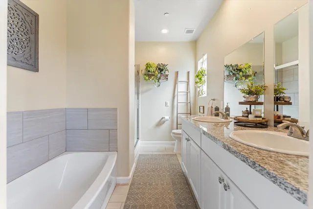 a spacious bathroom with a granite countertop tub a sink and a bathtub
