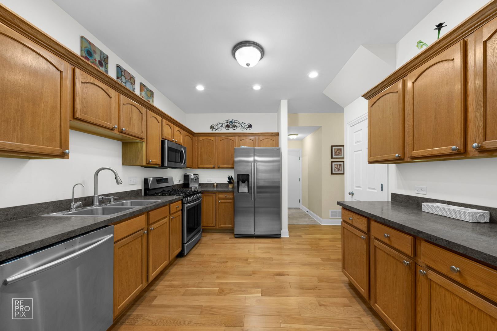 Undisclosed Address Elgin, IL 60120 - Photo 10 of 22 a kitchen with stainless steel appliances granite countertop a sink a stove top oven a refrigerator with wooden cabinets and floor