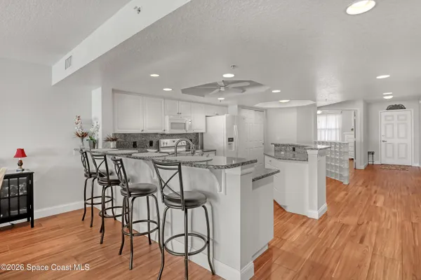 a kitchen with stainless steel appliances kitchen island granite countertop a table chairs sink and cabinets