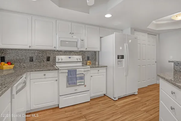 a kitchen with white cabinets and white appliances