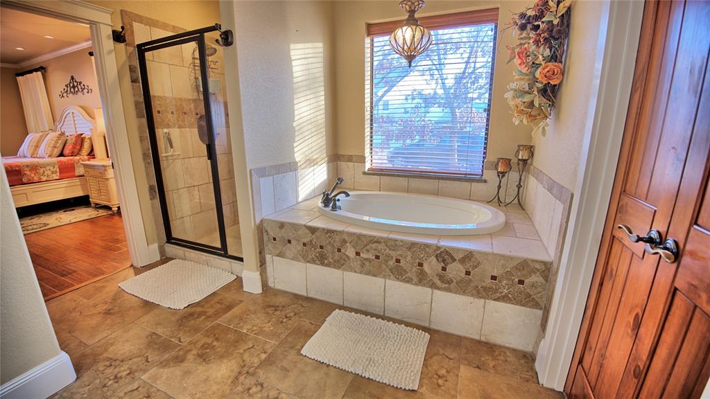 202 Storey Road Nocona, TX 76255 - Photo 25 of 40 a bathroom with a tub a sink and a large mirror next to a window