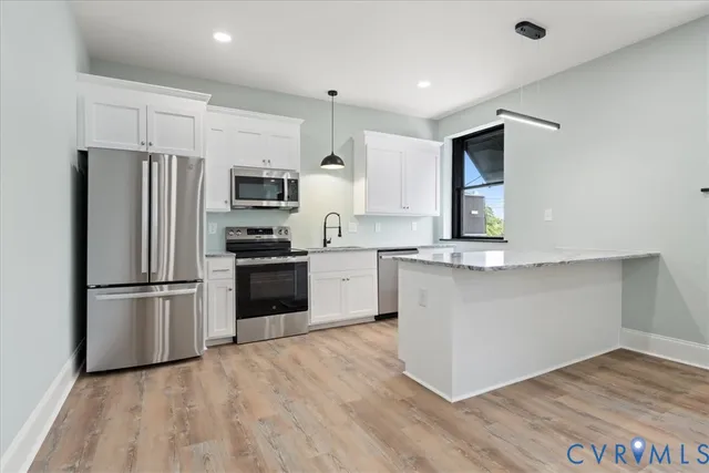 a kitchen with granite countertop a refrigerator and a stove top oven