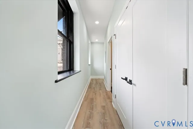 a view of a hallway with wooden floor and a bathroom