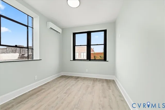 a view of an empty room with wooden floor and a window