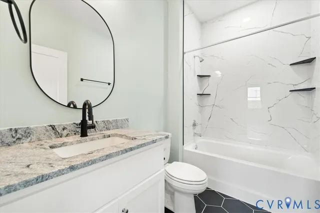 a bathroom with a granite countertop sink toilet a mirror and bathtub