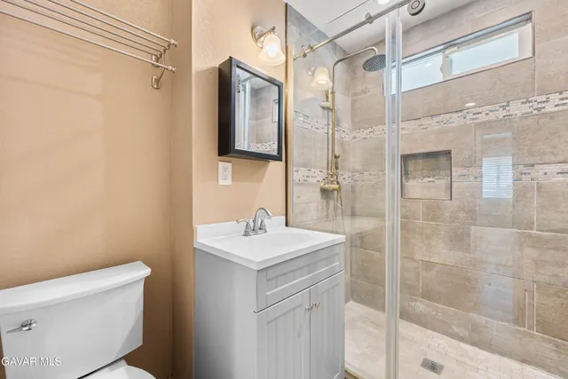 a bathroom with a sink a toilet a mirror and shower