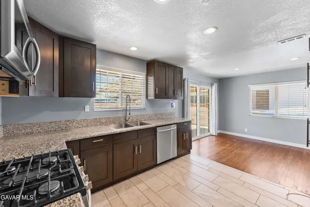 a large kitchen with granite countertop a sink and a stove top oven