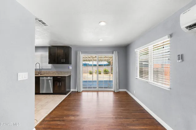 a view of a kitchen with a flat screen tv wooden floor and stainless steel appliances