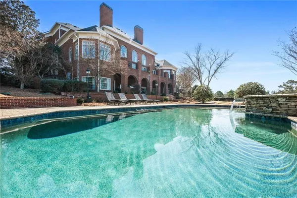 a view of a swimming pool with lawn chairs under an umbrella