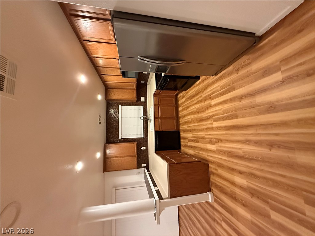 Warm wood cabinetry and matching flooring define this functional kitchen space with modern recessed lighting.