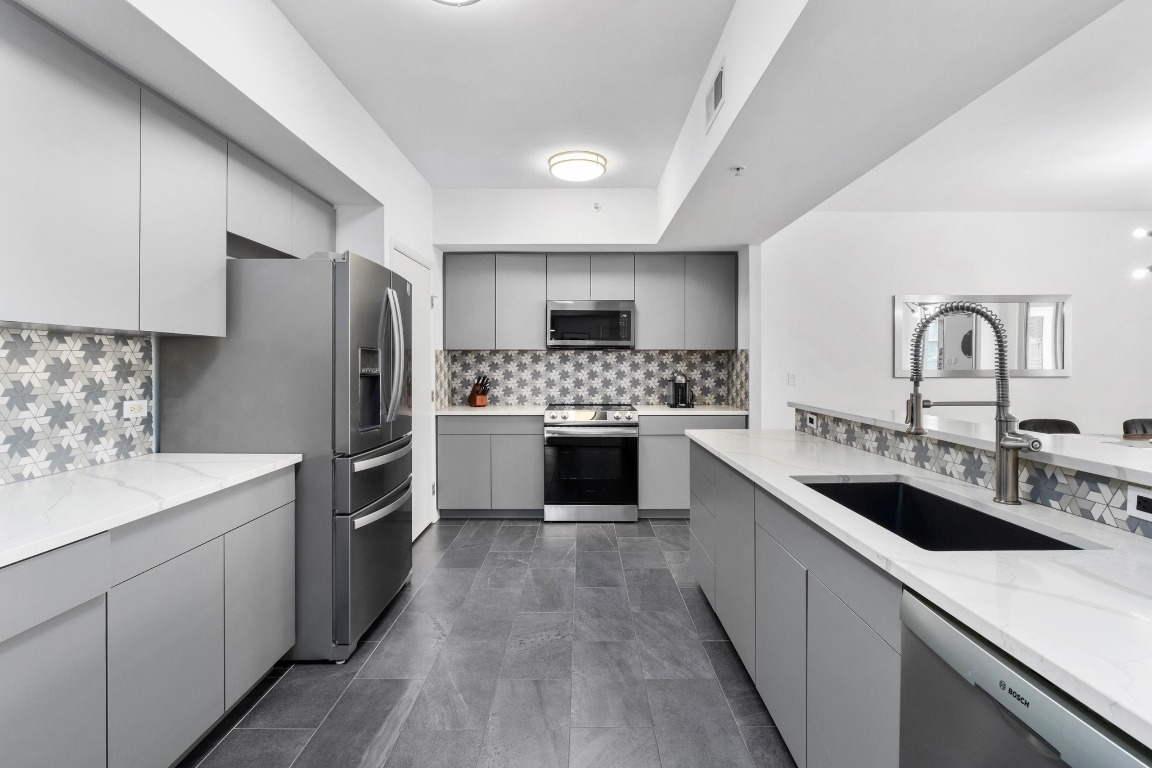 54 Rainey Street, Unit 1018 Austin, TX 78701 - Photo 7 of 33 a kitchen with a sink cabinets and stainless steel appliances
