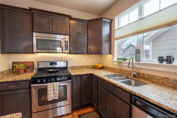 a kitchen with stainless steel appliances granite countertop a sink a stove and a refrigerator