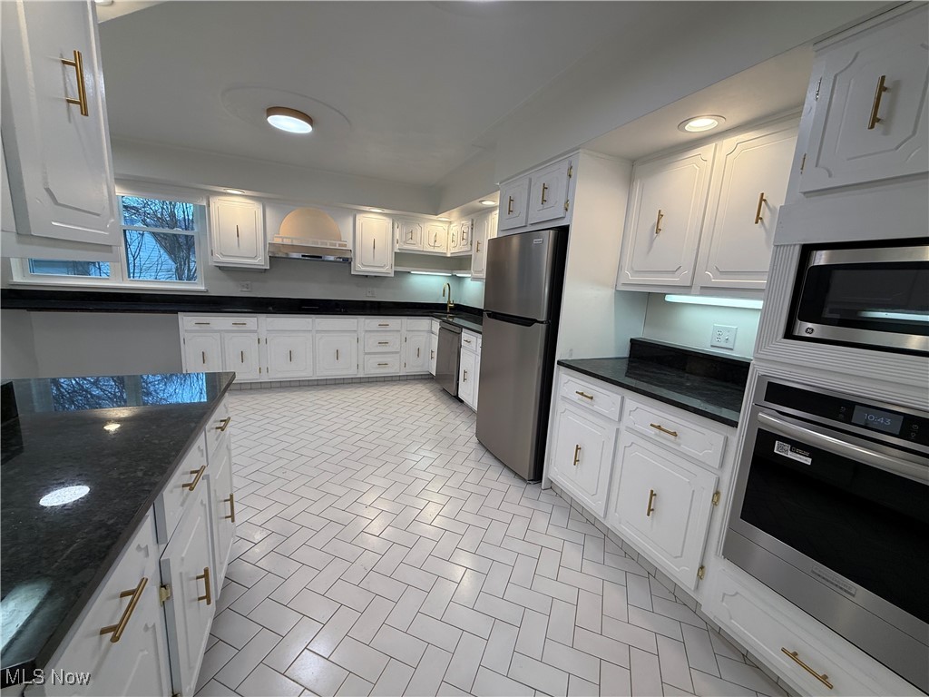 522 North 3rd Street Toronto, OH 43964 - Photo 9 of 47 Kitchen with appliances with stainless steel finishes, white cabinets, dark stone countertops, and under cabinet range hood