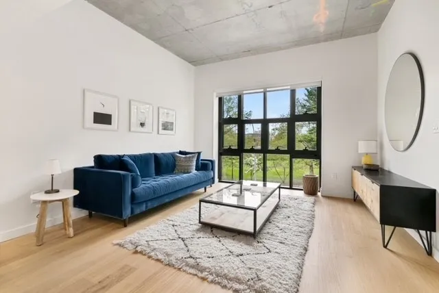 a living room with stainless steel appliances furniture a rug and a large window
