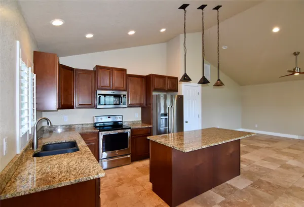 a kitchen with granite countertop a sink stainless steel appliances a window and a counter top space