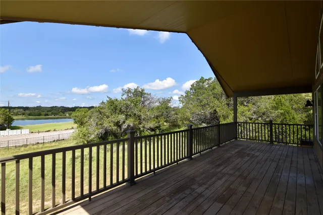 a balcony with wooden floor and yard in the back