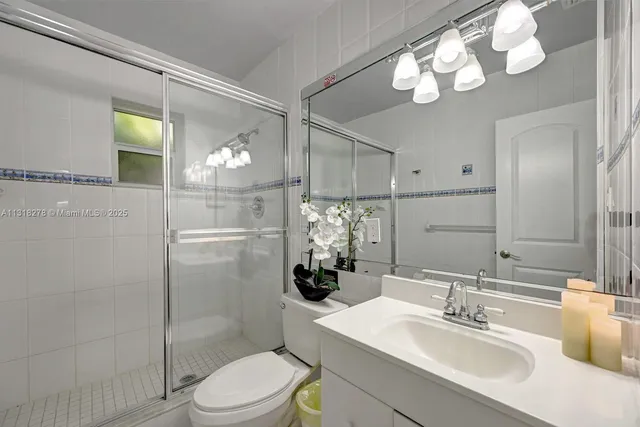 a bathroom with a sink vanity granite toilet and shower