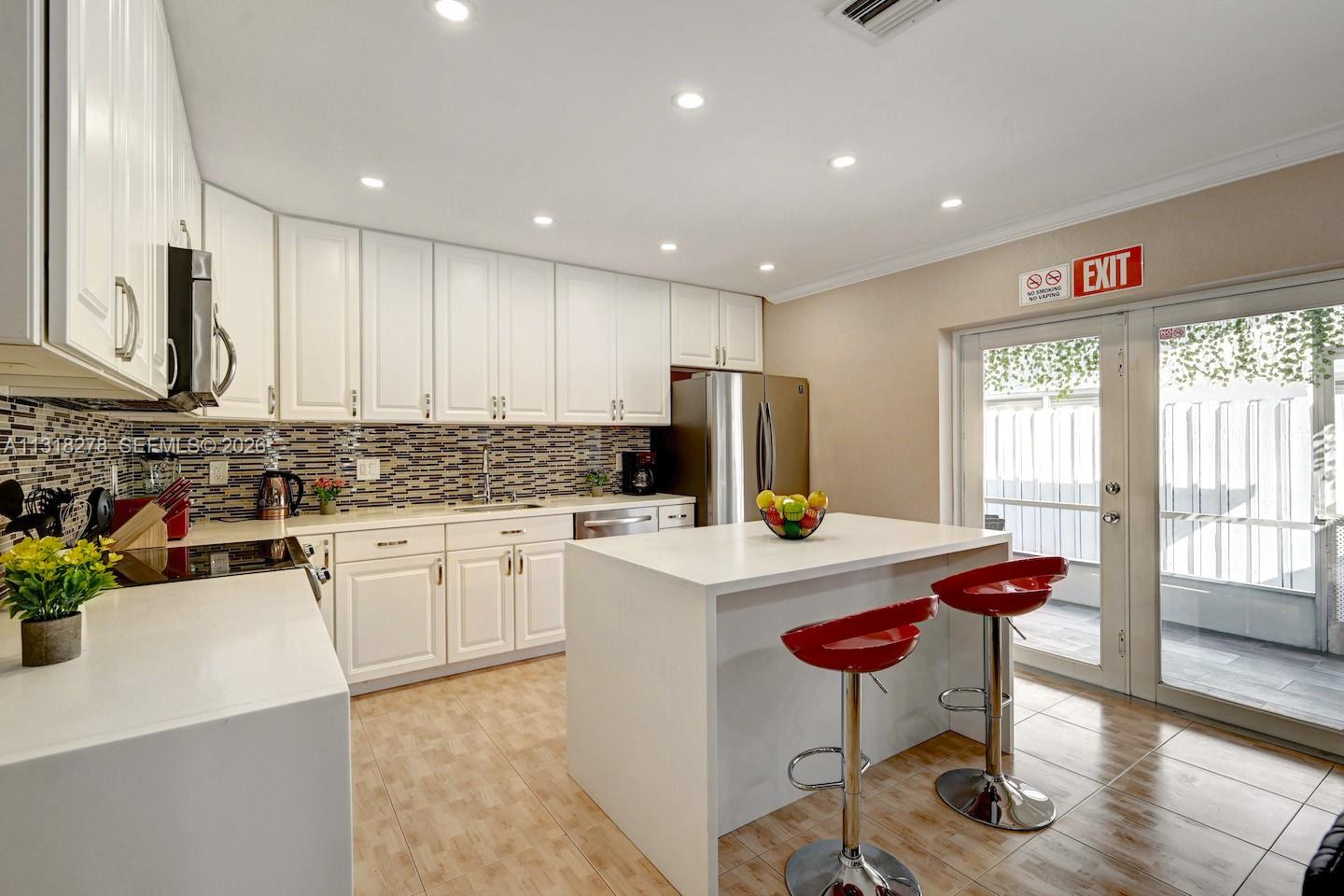 825 Harrison Street Hollywood, FL 33019 - Photo 9 of 37 a kitchen with stainless steel appliances granite countertop a stove refrigerator sink and white cabinets with wooden floor