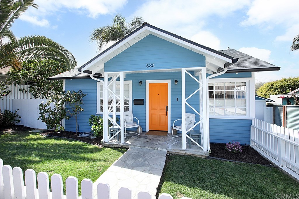 a view of a house with wooden fence and a yard