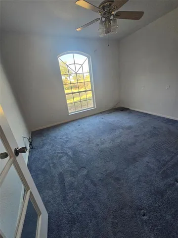 an empty room with windows and fan