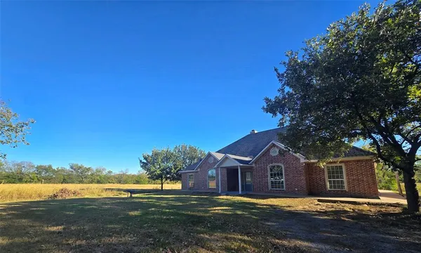 a view of a house with a big yard and large trees