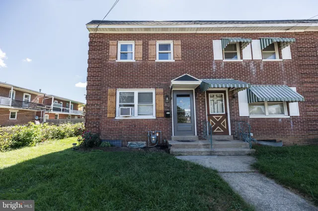 a view of a brick house with a yard and plants