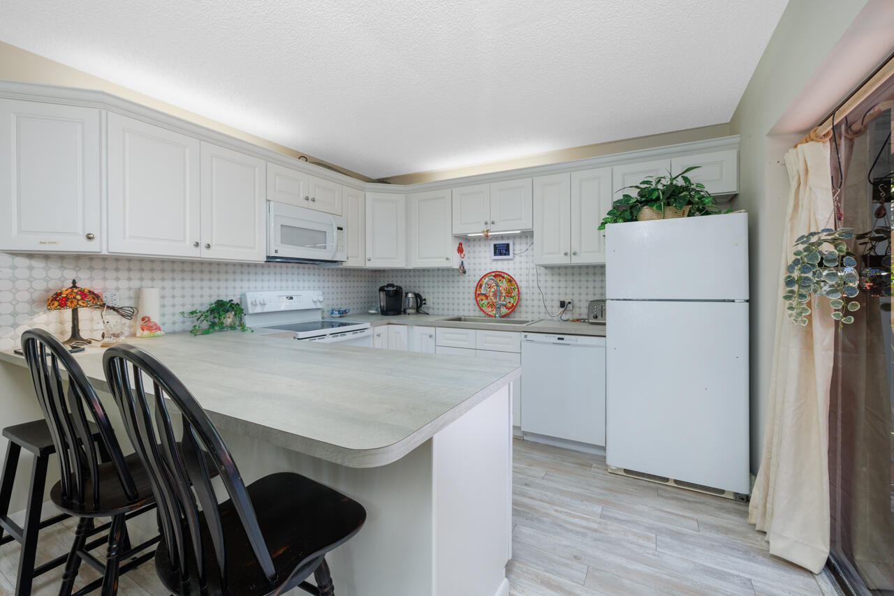 5996 Southeast Riverboat Drive, Unit 539 Stuart, FL 34997 - Photo 9 of 29 a kitchen with a refrigerator a stove a sink and white cabinets with wooden floor