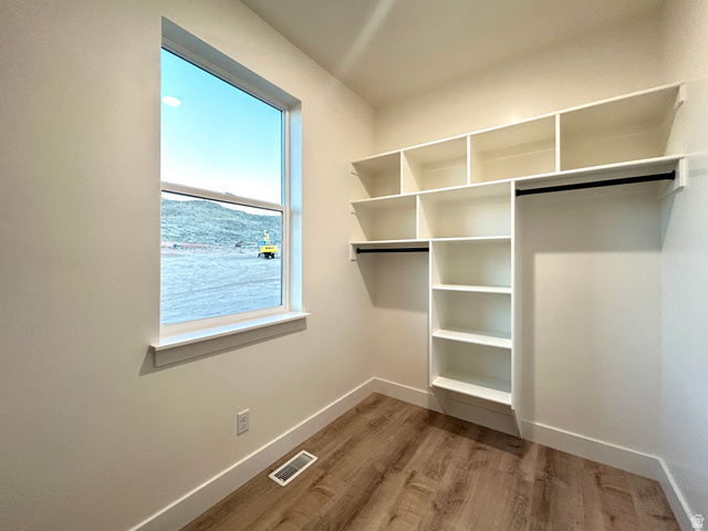 6 South 450th West Gunnison, UT 84634 - Photo 34 of 45 Walk-in closet featuring a window, built-in shelving, two hanging rods, and wood-finish flooring