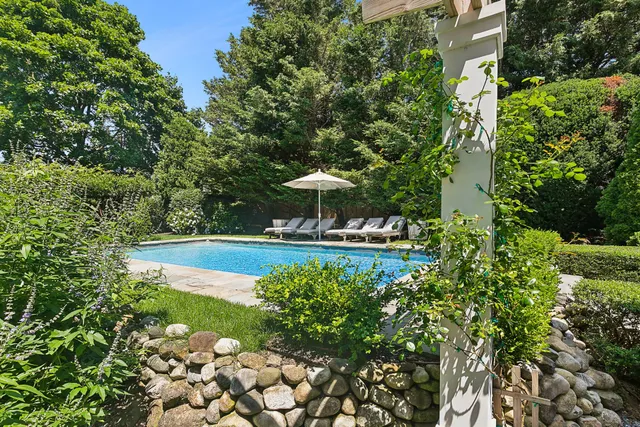 a view of a swimming pool with a bench and trees in the background