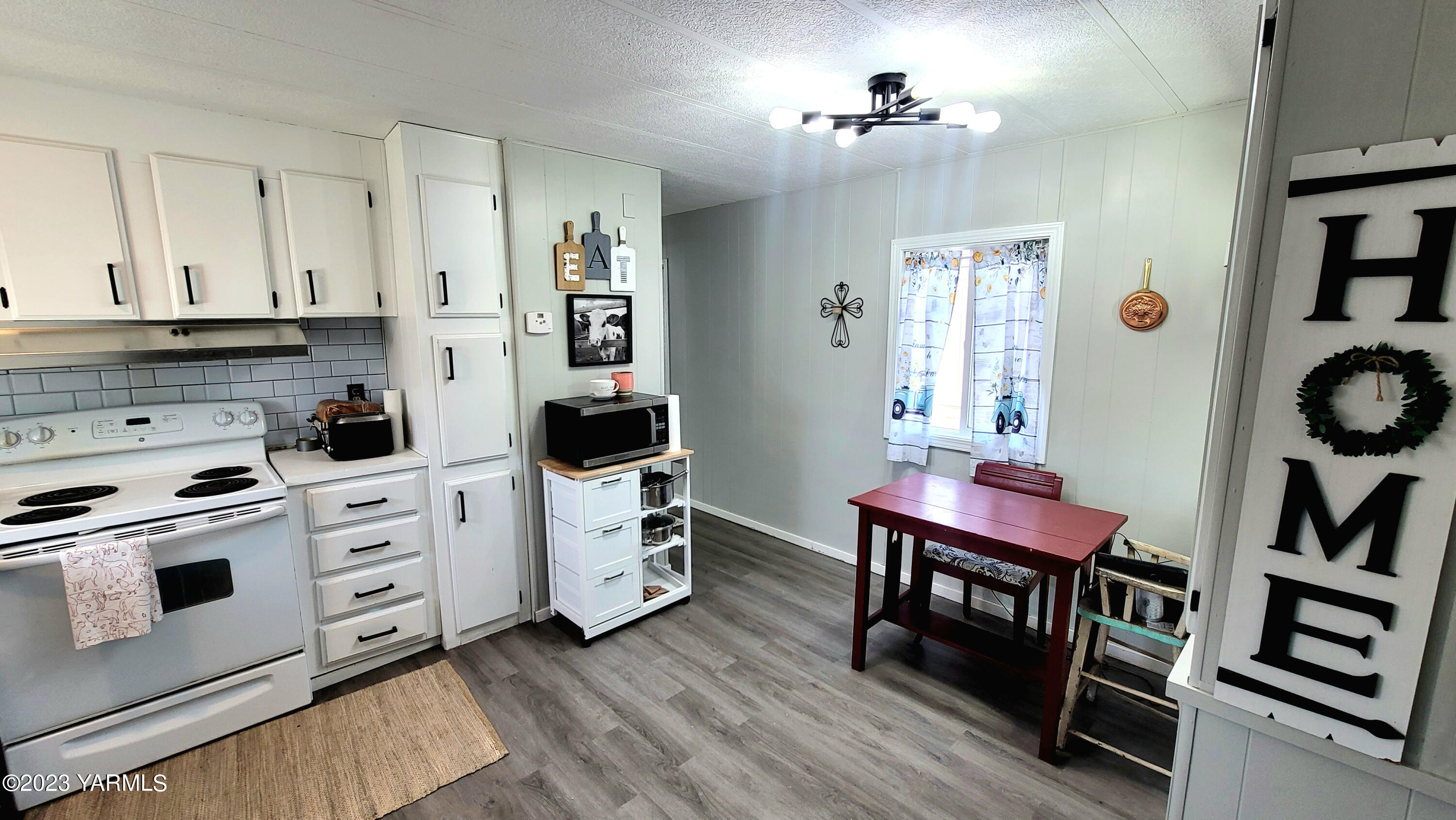 3005 Castlevale Road, Unit 26 Yakima, WA 98902 - Photo 3 of 12 a kitchen with stainless steel appliances a stove a chimney a dining table and chairs with wooden floor