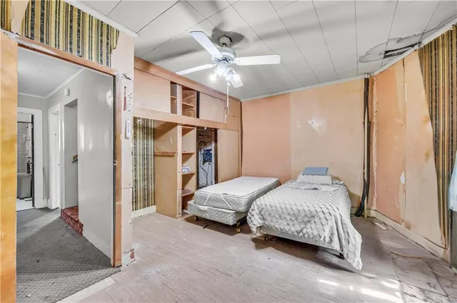 a bedroom with a bed ceiling fan and a large mirror