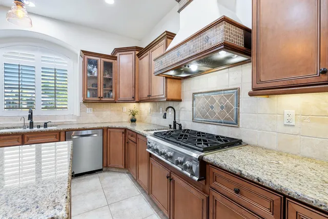a kitchen with granite countertop stainless steel appliances sink stove and cabinets