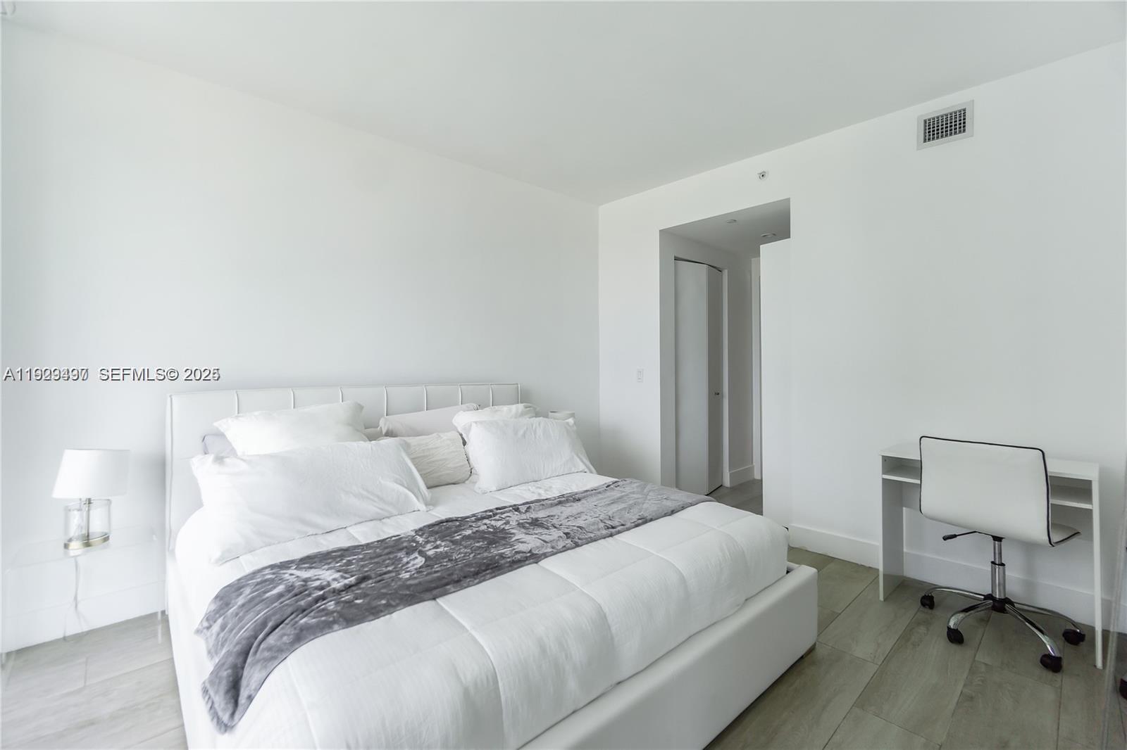 121 Northeast 34th Street, Unit 1203 Miami, FL 33137 - Photo 9 of 26 a bedroom with a bed and a chair