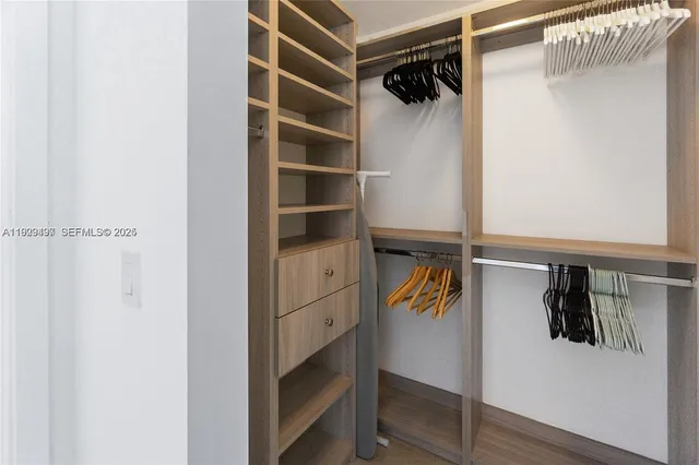 a view of walk in closet with clothes and shoes