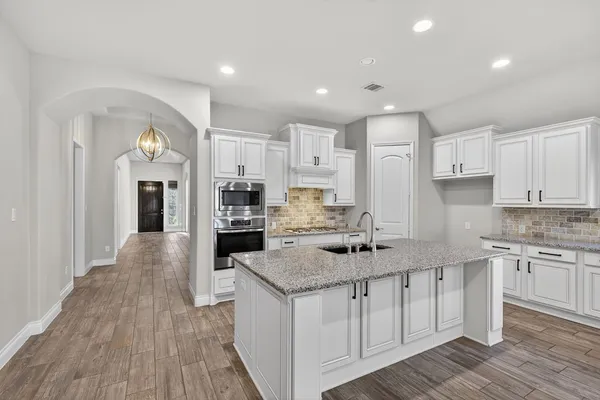 a large kitchen with stainless steel appliances granite countertop a lot of counter space and wooden floor