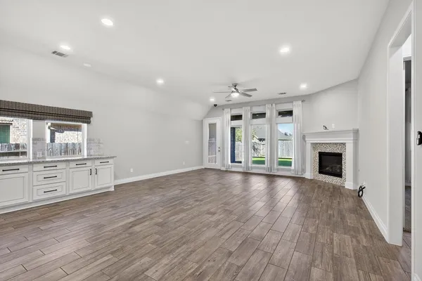 a view of an empty room with window and wooden floor