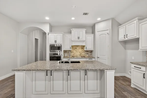 a kitchen with kitchen island granite countertop a stove a sink and a refrigerator