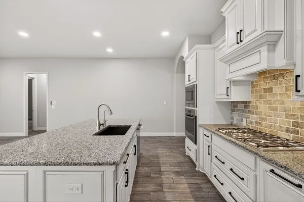 a kitchen with granite countertop a sink stove and cabinets