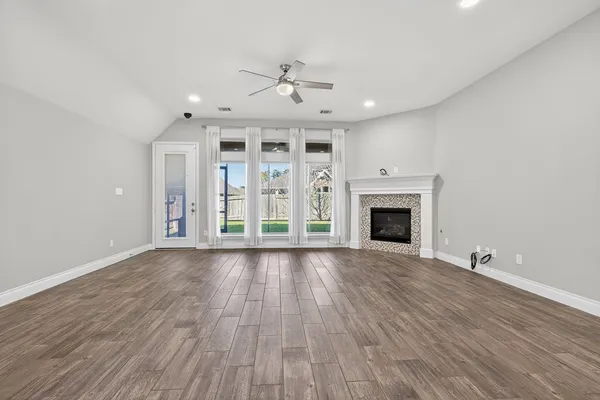 a view of an empty room with wooden floor fireplace and a window