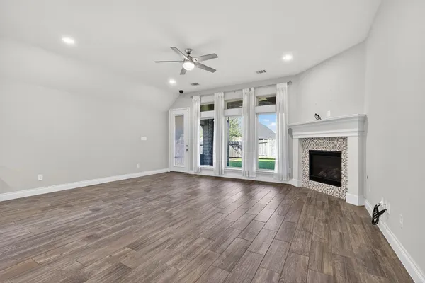 an empty room with wooden floor fireplace and windows