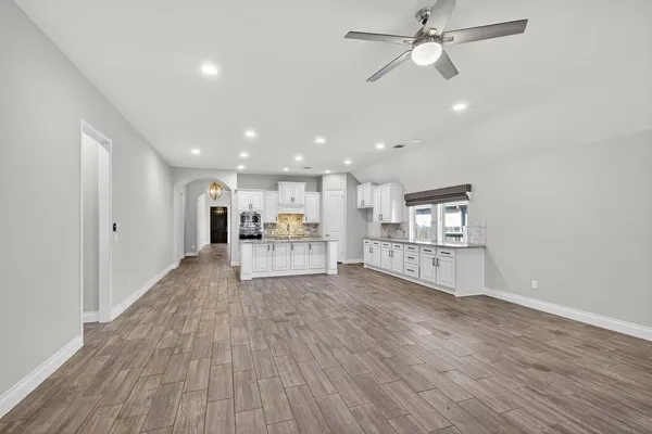 a living room with stainless steel appliances kitchen island hardwood floor and a view of kitchen