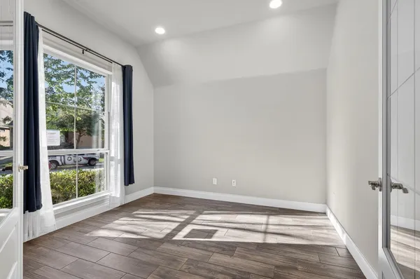 a view of an empty room with wooden floor and a window