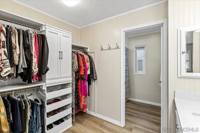 a view of walk in closet with clothes and shoes