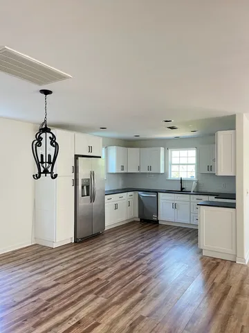 a large kitchen with stainless steel appliances granite countertop a refrigerator sink and white cabinets