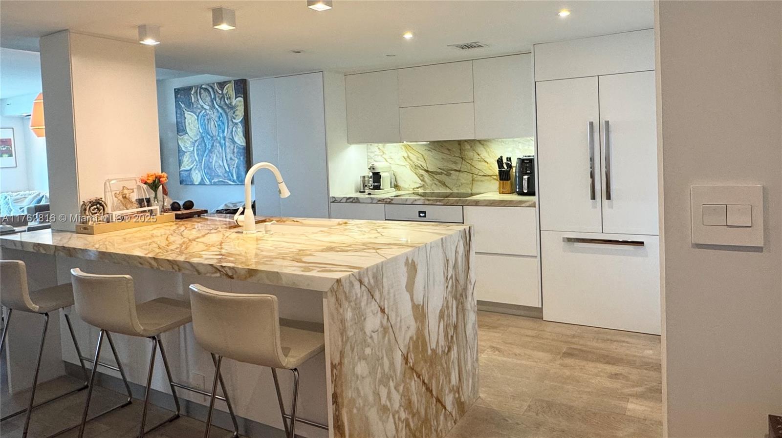2101 Brickell Avenue, Unit 1012 Miami, FL 33129 - Photo 25 of 40 a kitchen with kitchen island granite countertop a table chairs sink and cabinets