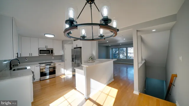 a large kitchen with granite countertop a stove top oven a sink dishwasher a dining table and chairs with wooden floor